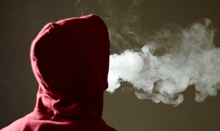 a hooded teenager vaping
