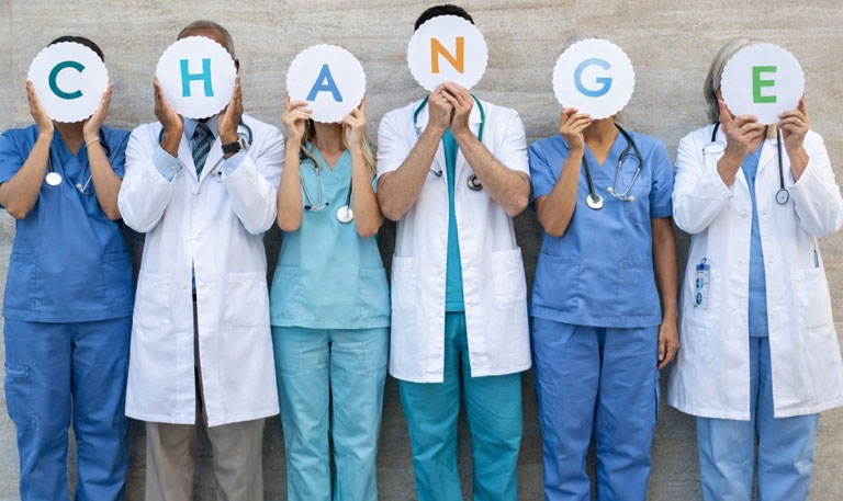 Health care workers hold up signs that spell out change