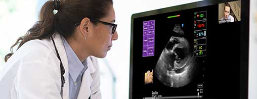 A clinician watching a virtual meeting on a computer screen