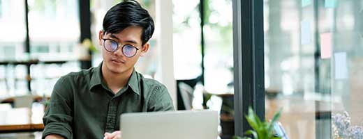 A man sits with a laptop in front of him