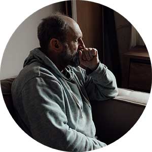 Elderly man sitting on a couch with a worried expression