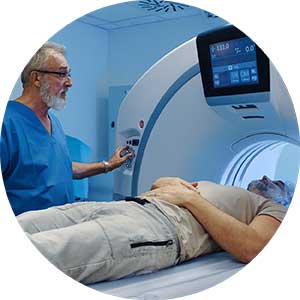 Male patient undergoing CT scan in a machine operated by a man wearing scrubs