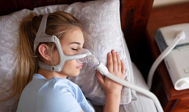 A woman sleeps with a positive airway pressure machine