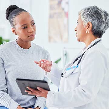 A woman in a white lab coat talks to a patient