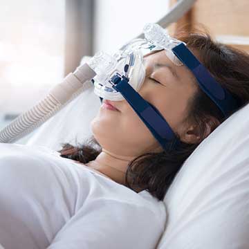 A woman wears a nasal CPAP mask