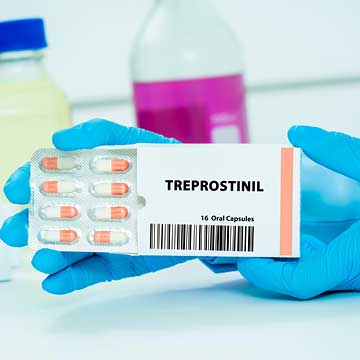 Someone wearing blue gloves holds pills labeled 