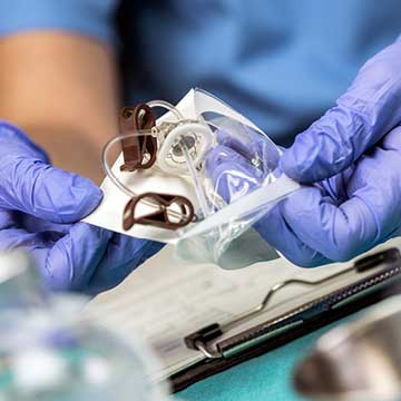 A person wearing gloves holds a venous catheter
