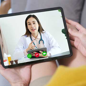 A person holds a tablet during a video chat with a doctor