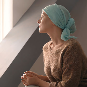 A woman wearing a head scarf looks off into the distance